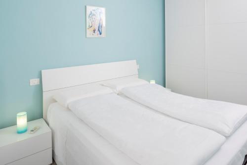 a white bed with white sheets and a candle on a table at Apartment Alba Gardena in Bardolino