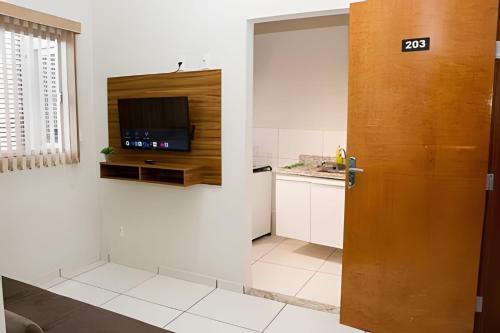 a room with a door with a tv and a kitchen at 103-FLAT-Espaço, conforto.É disso que você precisa in Anápolis