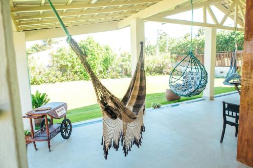 a porch with two hammocks hanging from the ceiling at Recanto Preocupação Zero in Morro Branco