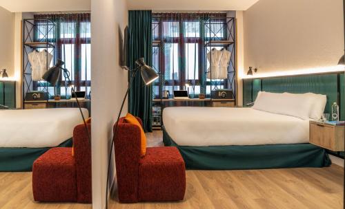 a hotel room with two beds and a chair at Axel Hotel Bilbao - Adults Only in Bilbao