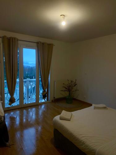 a bedroom with a bed and a large window at Appartement Chloé du lac in Montferrat