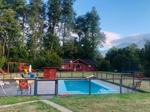 a fence around a swimming pool with a house in the background at Casa 1 de relajo con áreas verdes in Pucón