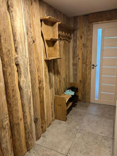 a room with a wooden wall with shelves and a door at Pūnas in Cēsis