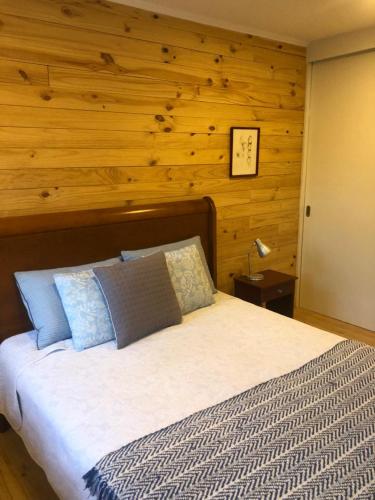 a bedroom with a bed with a wooden wall at Hermosa casa en el bosque in Algarrobo