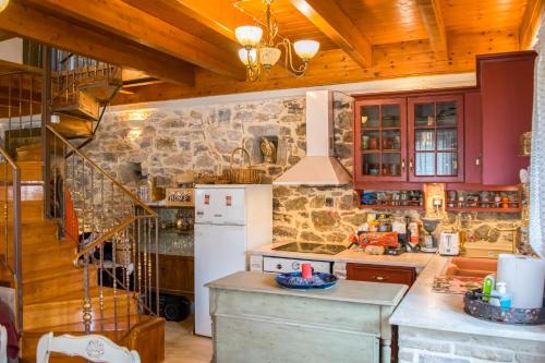 a kitchen with a white refrigerator and a stone wall at Kleitor Stone Villa-Peloponnese Getaway in Klitoria