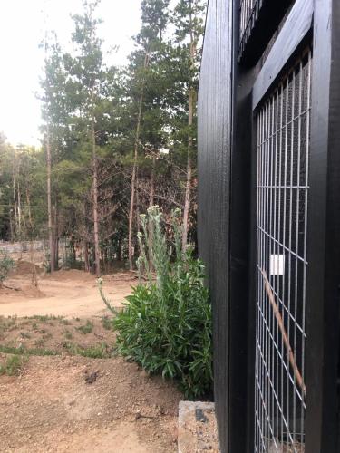 a black gate with a bush in front of a forest at Hermosa casa en el bosque in Algarrobo