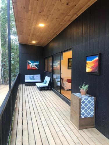 a wooden deck with a couch on a house at Hermosa casa en el bosque in Algarrobo