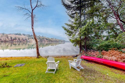 two chairs and a red raft on the grass near a lake at Hammersley Hideaway in Shelton