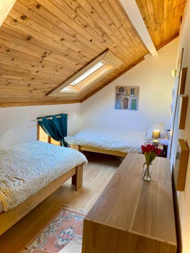 une chambre avec deux lits et un plafond en bois dans l'établissement La Miette, à La Celle-sous-Gouzon