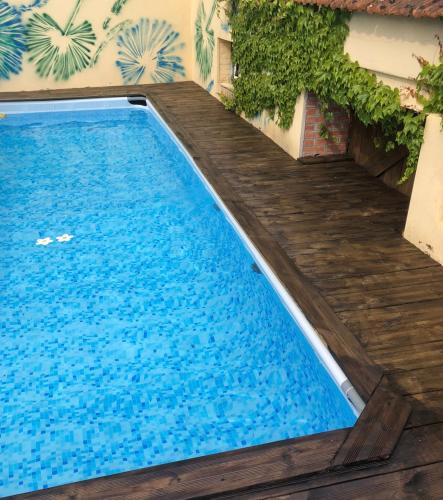 - une piscine avec une terrasse en bois à côté d'un bâtiment dans l'établissement La Miette, à La Celle-sous-Gouzon