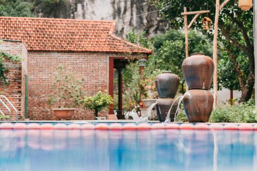 a swimming pool with three vases in front of a building at Tam Coc Lavender Homestay -Authentic Ninh Binh Experiences in Ninh Binh