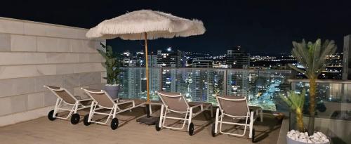 a group of chairs and an umbrella on a balcony at פנטאוז עצום נוף עוצר נשימה in Qiryat Yam