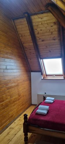 a bedroom with a bed with red sheets and a window at Kraljevi Konaci Olja in Zlatibor