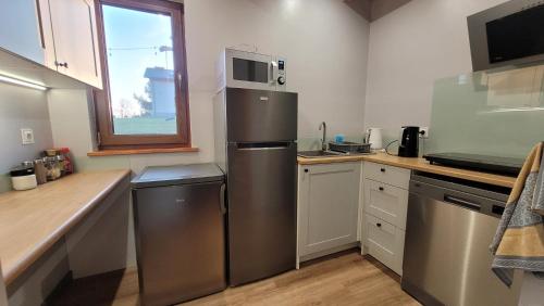 a kitchen with a stainless steel refrigerator and a window at Wrzosowe Wzgórze in Chęciny
