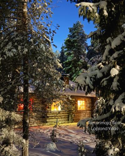 a log cabin in the snow at night at Lapland Tunturimaja Ski in, sauna, wifi, in Pyhä center - Lapland Villas in Pyhätunturi