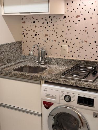 a kitchen with a sink and a washing machine at Flat Sudoeste Vienna by CentoEdez in Brasília