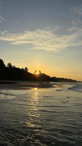 a sunset on a beach with the sun setting at Sagarika Beach Hotel in Moragalla