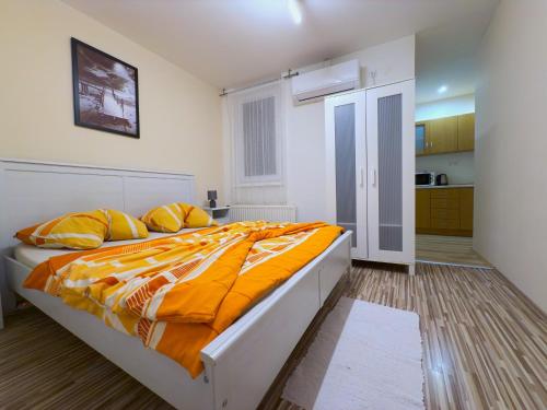 a bedroom with a large bed with orange sheets and yellow pillows at Apartmány Hillfort in Bojnice