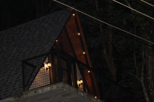 a window of a house at night with lights at Cicadas Nature Resort - A Frame cottages in Wayanad