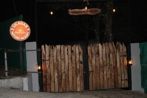 a wooden gate in front of a building with a sign at Cicadas Nature Resort - A Frame cottages in Wayanad