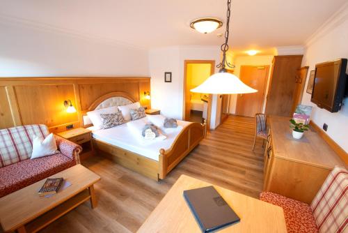a room with a bed and a couch and a table at Aktiv & Wellnesshotel Zentral in Prato allo Stelvio