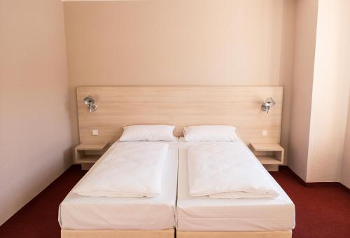 2 Betten in einem kleinen Zimmer mit weißer Bettwäsche in der Unterkunft Rasthof & Motel Hermsdorfer Kreuz in Hermsdorf