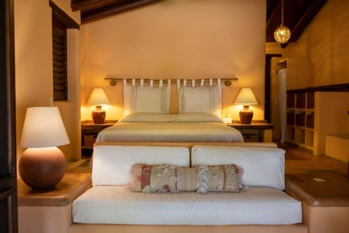 a bedroom with a bed and a couch with two lamps at Puertas Paraíso Hotel boutique in Zihuatanejo