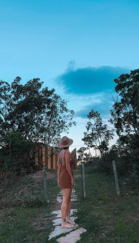 a woman in a hat standing on a path at Chalé charmoso e aconchegante, pertinho da cidade. in Brasilia