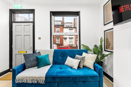 a blue couch in a living room with a window at Designer 4 Bed House in Leeds - Sleeps 13 in Leeds