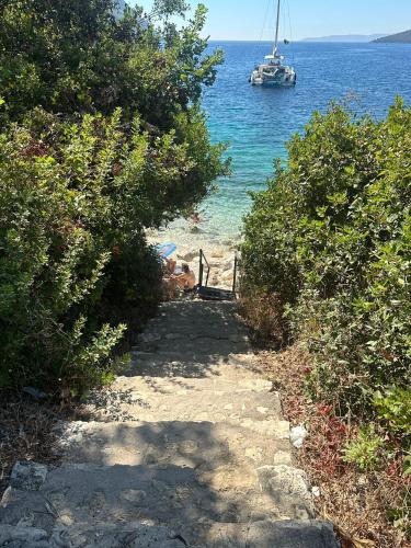 a path leading to the beach with a boat in the water at Aella Exclusive Residences Lefkada in Mikros Gialos
