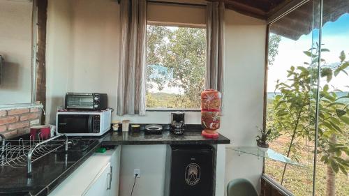 a kitchen with a counter with a microwave and a window at Chalé charmoso e aconchegante, pertinho da cidade. in Brasilia