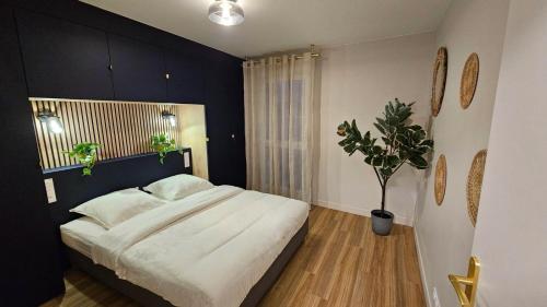 - une chambre avec un grand lit et une plante en pot dans l'établissement L'Écrin Bleu, à Aubervilliers