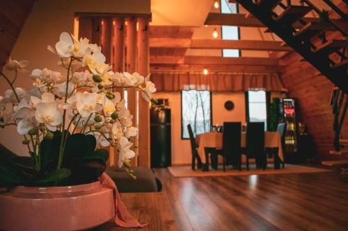 a vase filled with white flowers on a table at Dom Chalet in Tisău