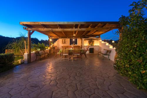 a patio with a table and chairs under a wooden pergola at Natura House in Ialyssos