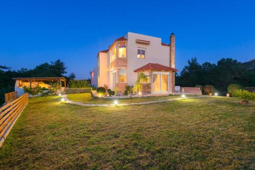 a large house with lights on a yard at night at Natura House in Ialyssos