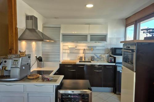 eine Küche mit weißen Schränken und schwarzen Geräten in der Unterkunft Appartement cosy au cœur de La Féclaz in La Feclaz