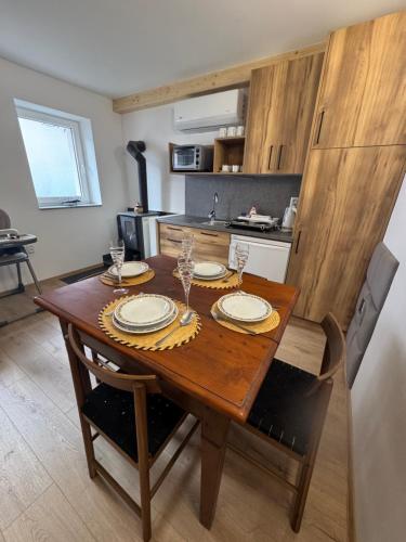 a kitchen with a wooden table with plates and glasses at Chalupa DEMÄNOVÁ in Liptovský Mikuláš