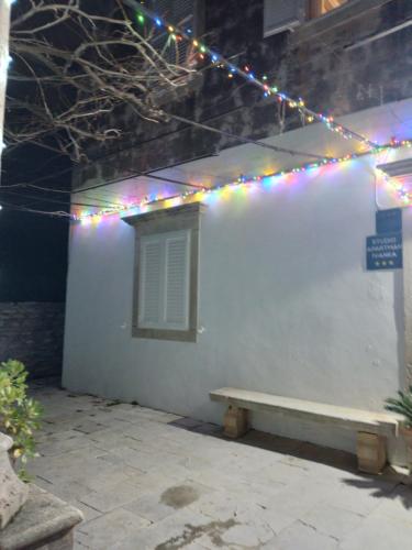 a white building with a bench and christmas lights at Studio Apartman Ivanka in Orebić