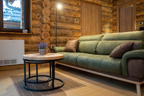 a living room with a green couch and a table at Aurum Cabins in Zlatibor