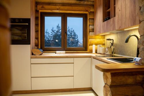 a kitchen with white cabinets and a window at Aurum Cabins in Zlatibor