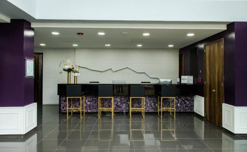 a lobby with a bar with stools and purple walls at Hotel Roseliere Bucaramanga in Bucaramanga
