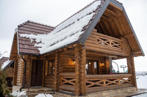 a log cabin with snow on the roof at Aurum Cabins in Zlatibor