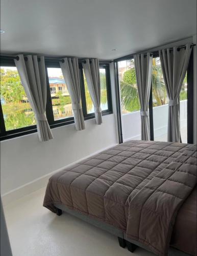 a bedroom with a large bed in front of windows at Villa Nature Tropicale Lac au Centre Ville de Koh Samui Chaweng in Koh Samui