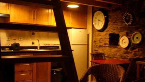 a kitchen with a clock on a stone wall at Casa Cima in Chãs de Égua