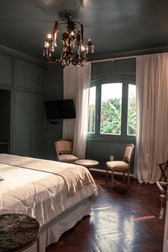 a bedroom with a bed and chairs and a chandelier at Casa Lola in Yerba Buena
