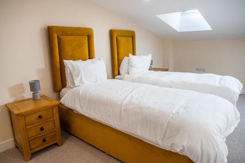 a bedroom with two beds and a night stand at Bears Court Barn 7 in Cheltenham