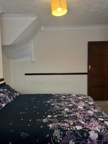 a bedroom with a bed with a floral bedspread at JXB HOMES - Lovely and spacious rooms in Kent