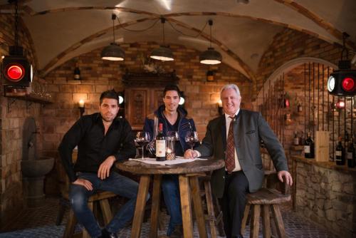 a group of three men sitting at a table with wine glasses at Hotel Gasthof Brücke in Mayrhofen