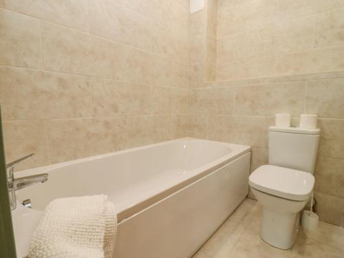 a bathroom with a white tub and a toilet at Bears Court Barn 2 in Cheltenham
