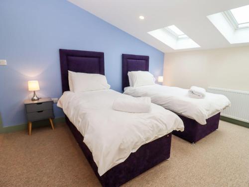 two beds in a room with blue walls and windows at Bears Court Barn 3 in Cheltenham